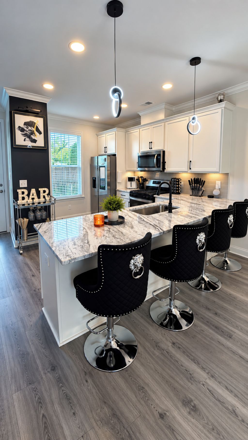 A modern kitchen with a marble countertop, stainless steel appliances, and black bar stools.