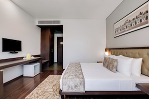 Habitació d'hotel amb llit, televisió, escriptori i un quadre al mur.