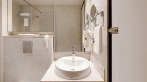 A modern bathroom with a large mirror, a sink, and a towel rack. - The Phlox Hotel (Hubballi)