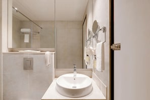 Een moderne badkamer met een grote spiegel, een wastafel en een handdoekhouder.
