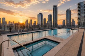 A rooftop pool with a city skyline view during sunset. - Modern Miami 2BR Suite | Sleeps 4 | Pool & Gym (Miami)