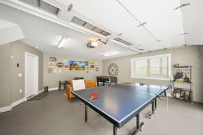 Ein Zimmer mit einem Tischtennis-Tisch, einer Uhr und unterschiedlichen Wanddekorationen.