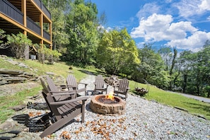Eine Terrasse mit Adirondack-Stühlen, einem Feuerkorb und einer Steinmauer.