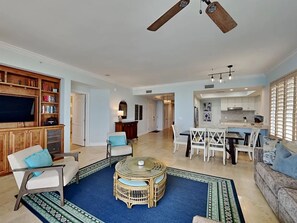Ein geräumiges Wohnzimmer mit Fernseher, Sitzgelegenheiten, Essbereich und Küche.