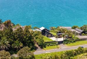 A coastal property with a large house, a swimming pool, and a road leading to the sea. - Sea Views & Space to Play (Waiheke Island)