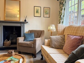 A cozy living room with a fireplace, a sofa, a chair, and a lamp. - Hampshire Cottage in Hartley Wintney (Hartley Wintney)