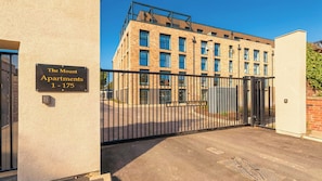 A gated entrance to The Mount Apartments, featuring a modern brick facade and a clear sky. - 2BR Apartment with City Views and Parking (Leeds)