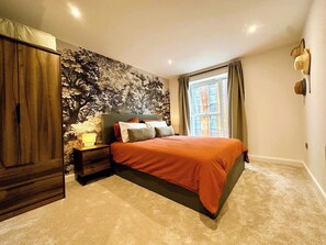 Une chambre à coucher avec un lit, des tables de chevet, une armoire et une fenêtre avec des rideaux.