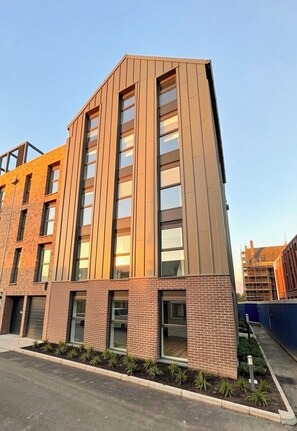 Un immeuble à plusieurs étages, doté d’une façade en briques et de grandes fenêtres.
