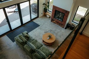 A modern living room with a green sofa, a round coffee table, and a fireplace. - NEW | Luxury Lakefront | Hot Tub, Beach & fishing (Backus)