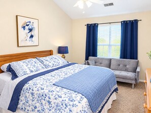 A bedroom with a bed, a grey sofa, a ceiling fan, and a window with curtains. - Four Kings and Four Baths, Your Retreat by the Strip (Branson)