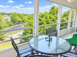 A balcony with a glass table and chairs, overlooking a green landscape and a parking area. - Four Kings and Four Baths, Your Retreat by the Strip (Branson)