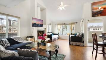 A spacious living area with a fireplace, a sofa, a dining table, and a view of the city.