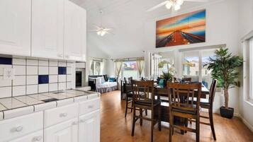 A spacious kitchen with white cabinets, a dining area with wooden chairs, and a ceiling fan.