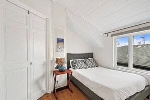 A bedroom with a bed, a nightstand, a window, and a door. - MB! 6BR Beachhouse- 4 parking spaces Sleeps 20+ (San Diego)