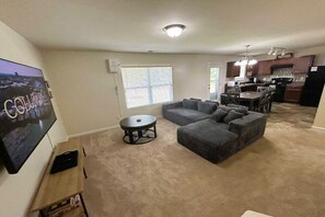 Ein Wohnzimmer mit einem Ecksofa, einem runden Couchtisch und einem flachbildschirmfernseher an der Wand.