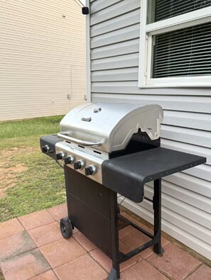 Ein tragbarer Grill mit Bedienfeld und flacher Grillplatte, platziert auf einer gefliesten Terrasse.