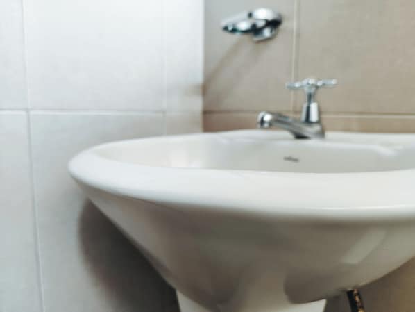 Un baño con lavamanos blanco, grifo y espejo.