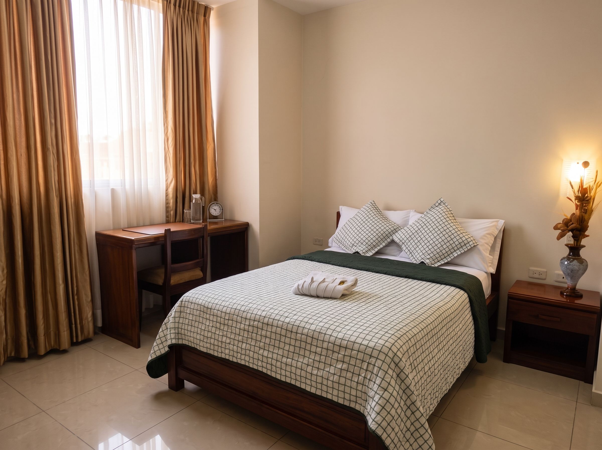 A bedroom with a bed, a nightstand, a desk, and a chair.