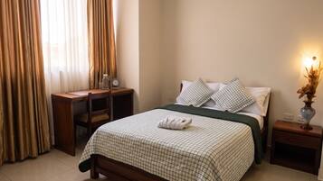 A bedroom with a bed, a nightstand, a desk, and a chair.