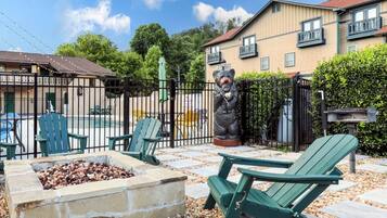 A patio area with Adirondack chairs, a fire pit, and a bear statue.