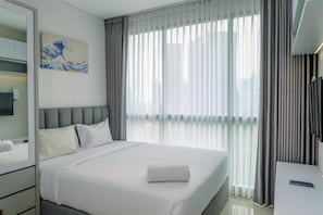 Ein Hotelzimmer mit einem Bett, einem Nachttisch, einem Spiegel, einem Gemälde und einem Fenster mit Vorhängen.
