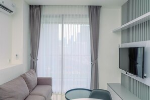 Ein modernes Wohnzimmer mit Sofa, Flachbildfernseher und Essbereich.