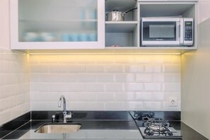 Eine moderne Küche mit einer Edelstahl-Spüle, einem Gasherd, einer Mikrowelle und einem Schrank über der Spüle.