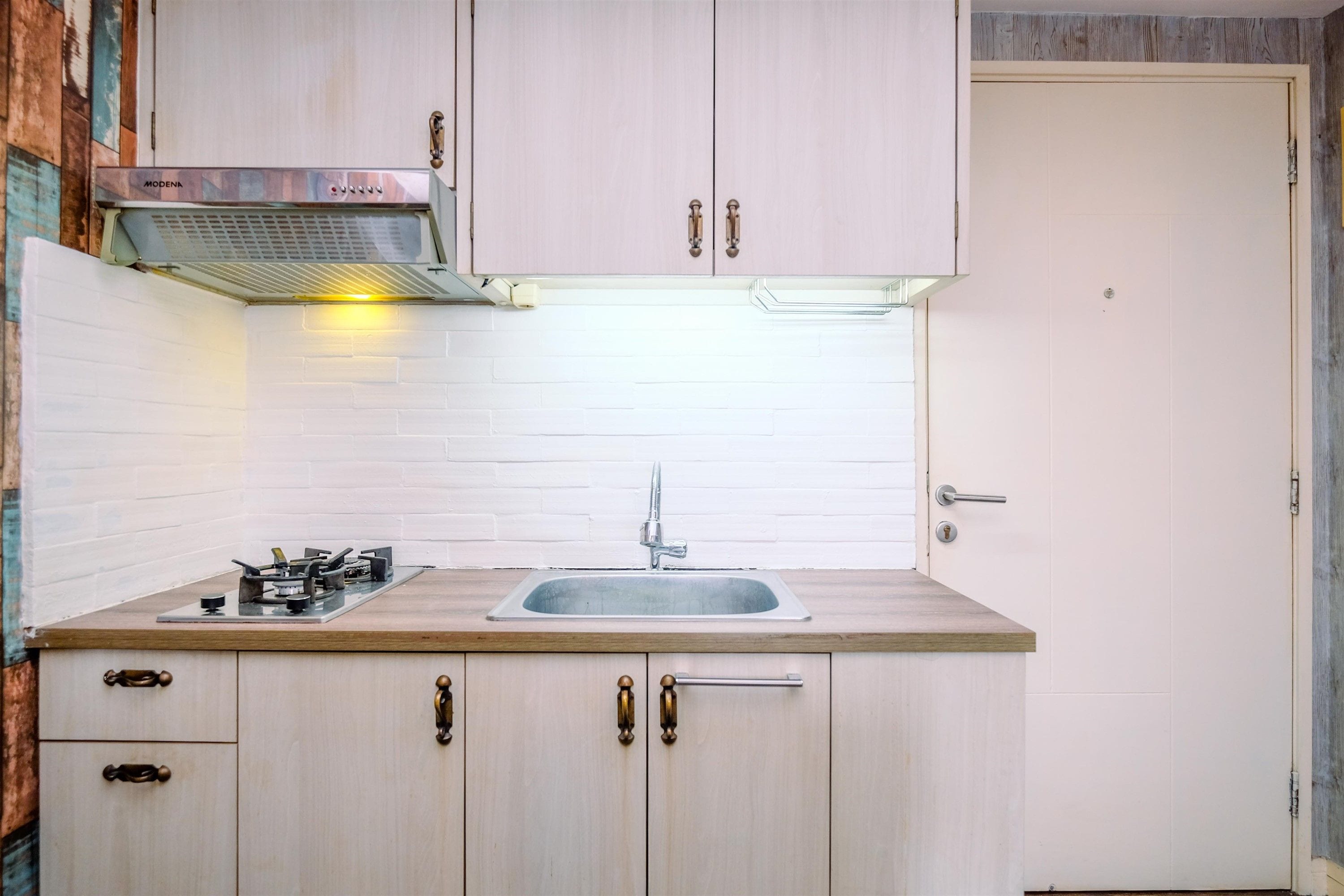Una cocina con un lavaplatos de acero inoxidable, armarios de madera y una estufa a gas.
