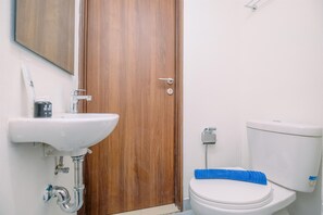 Ein Badezimmer mit einem weißen Waschbecken, einer Holztür und einer Toilette mit einem blauen Reinigungstuch.