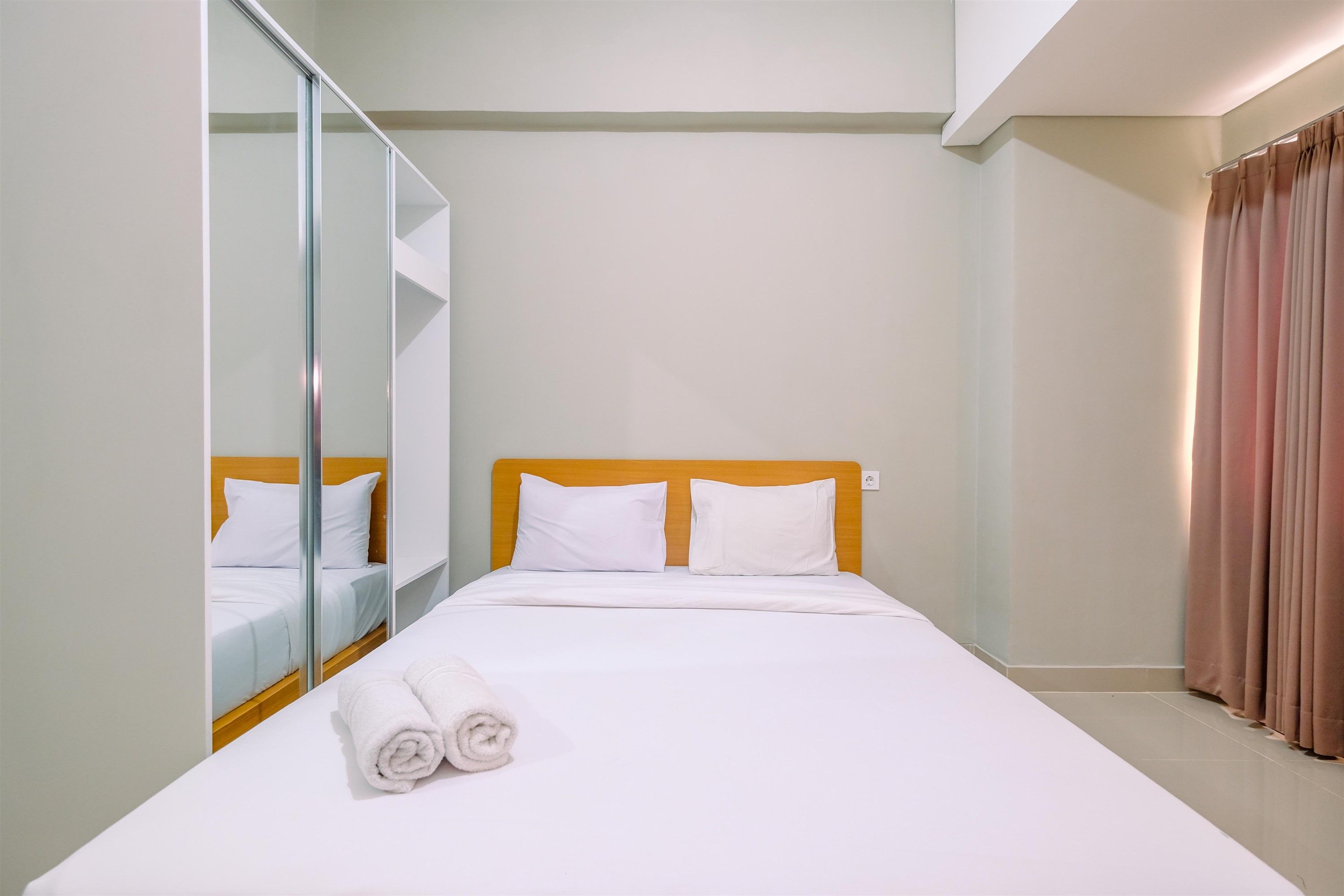 A hotel room with a bed, a mirror, and a curtain.