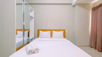 A hotel room with a bed, a mirror, and a curtain.