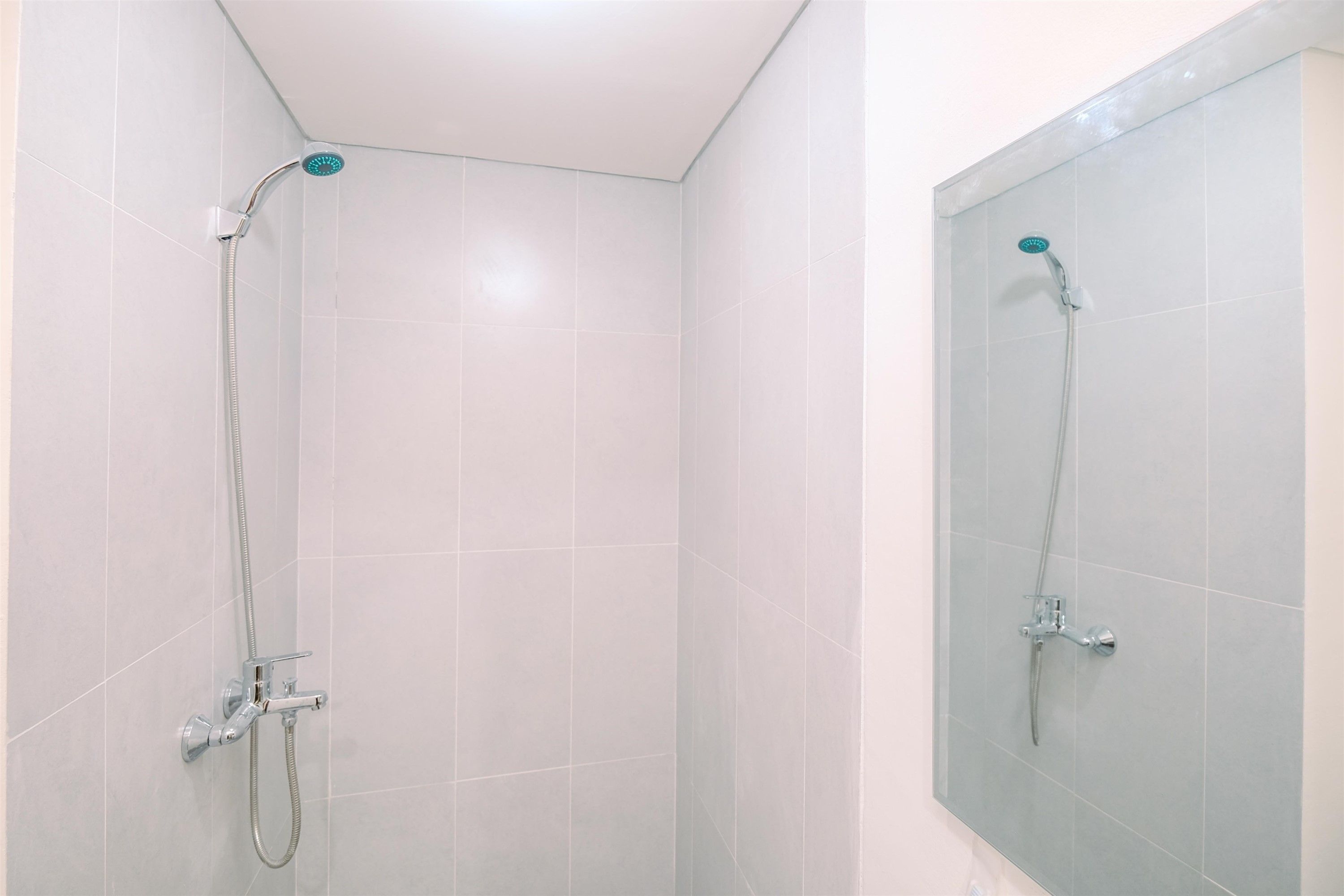 A shower area with a handheld showerhead and a wall-mounted faucet.