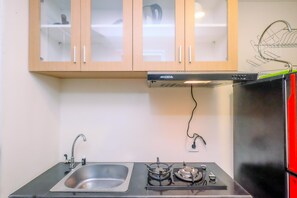 Une cuisine compacte équipée d’une cuisinière à gaz, d’un évier et de meubles en bois avec des portes en verre.