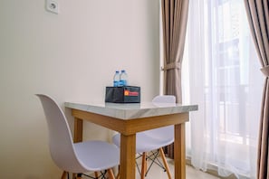 Un petit coin repas avec une table, deux chaises, une bouteille d’eau et un sac de voyage.