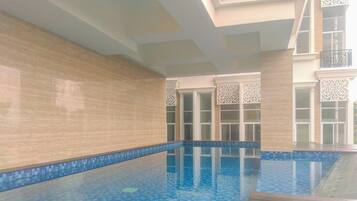 An indoor swimming pool with clear blue water, tiled walls, and a wooden deck.