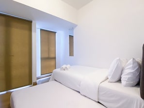 Ein Hotelzimmer mit zwei Betten, einem Fenster und einem Spiegel.