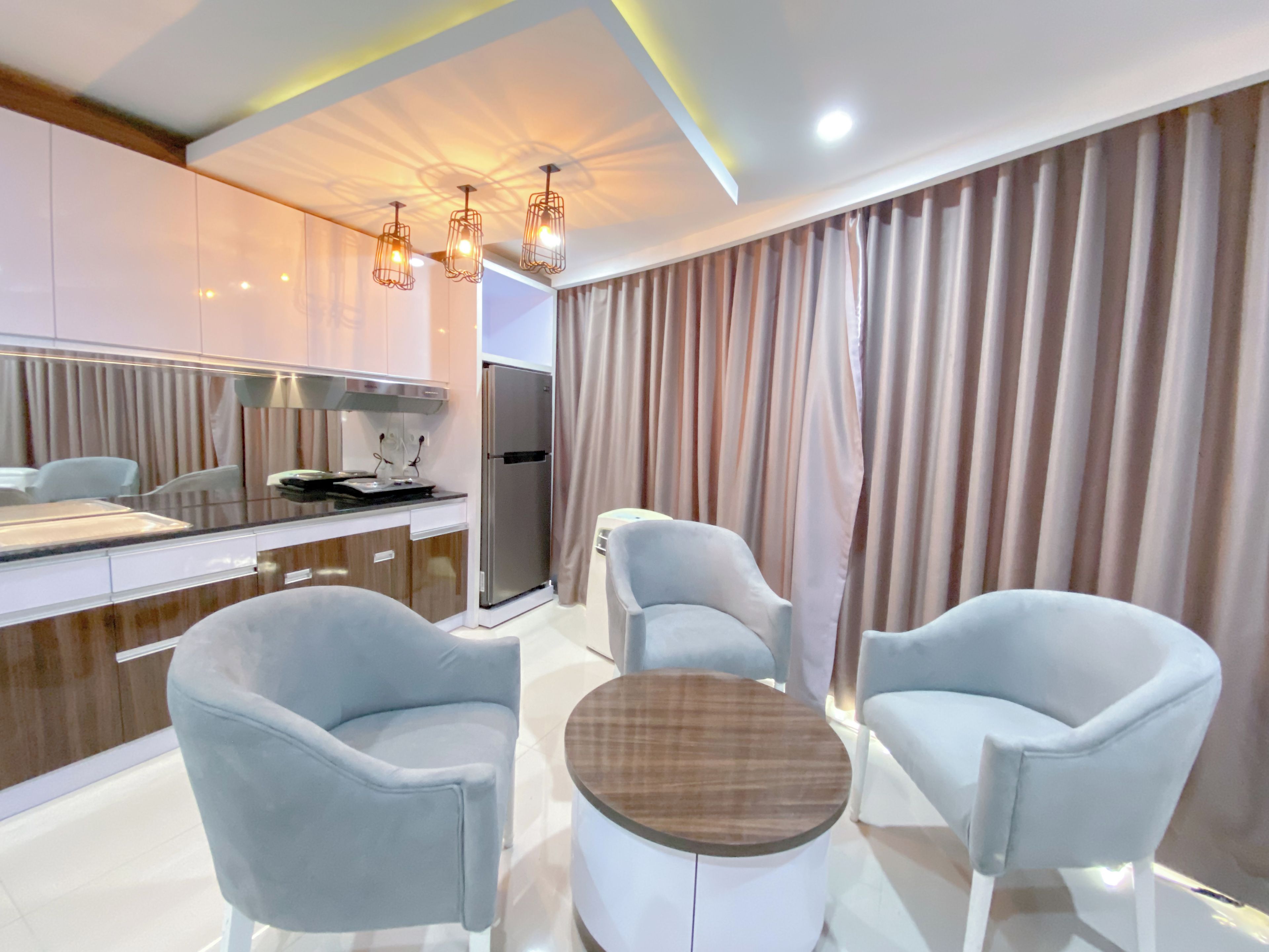 A modern kitchen with a refrigerator, stove, and dining area with chairs and a table.