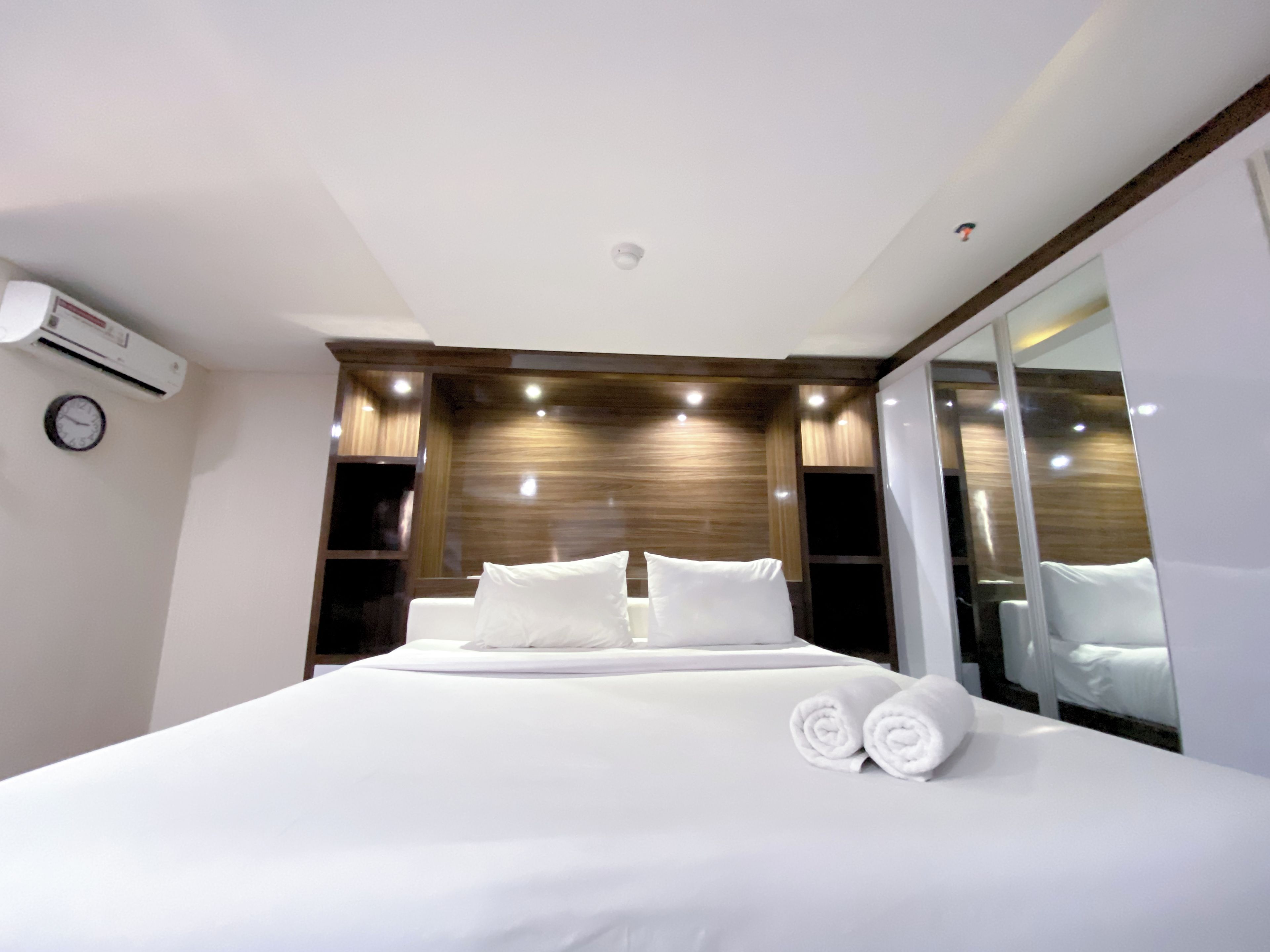 A modern hotel room with a large bed, a built-in wardrobe, and a large mirror.