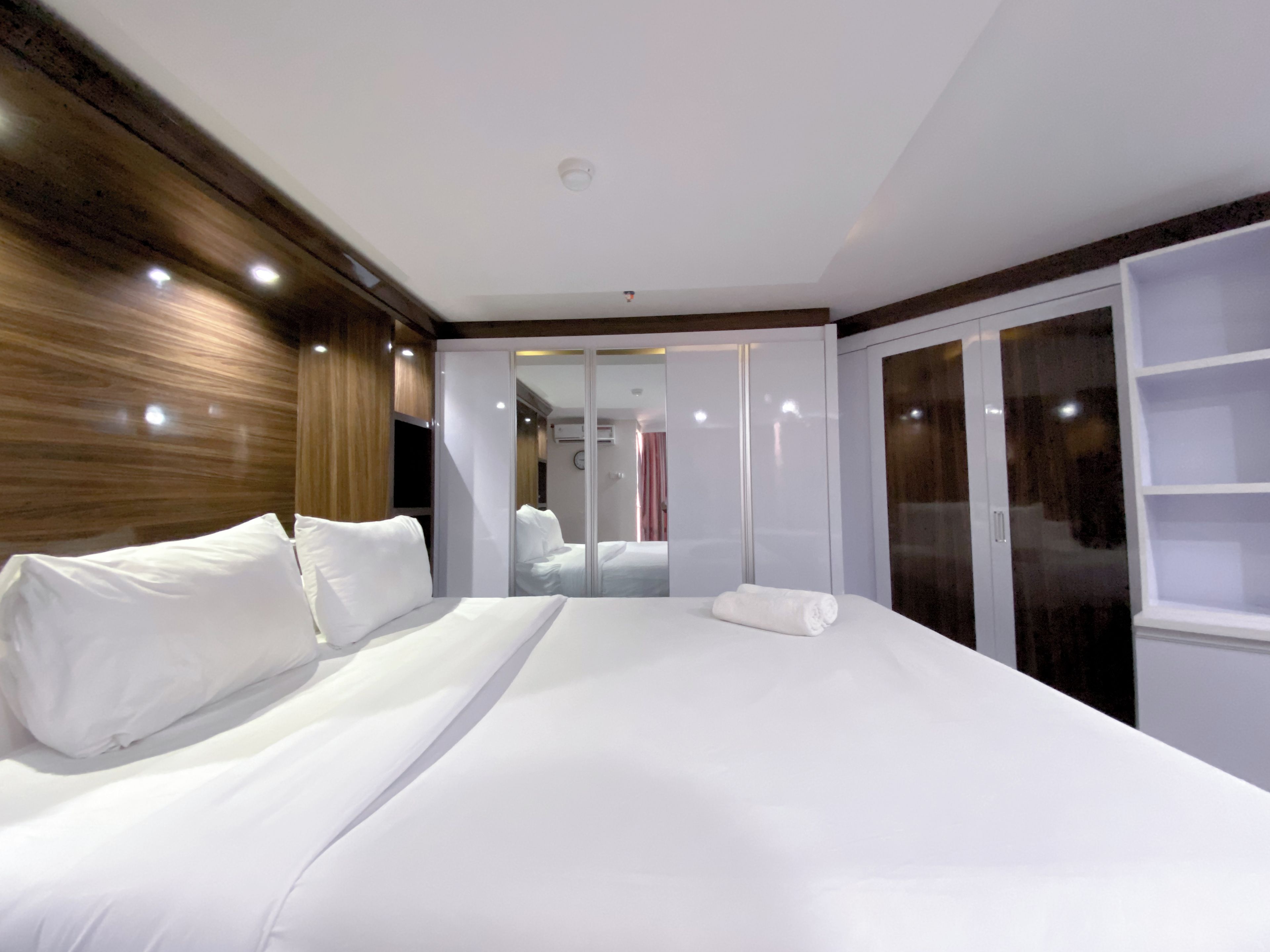 Una habitación de hotel con una cama grande, un armario y un espejo.