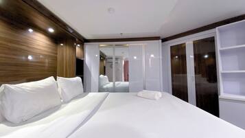 Una habitación de hotel con una cama grande, un armario y un espejo.