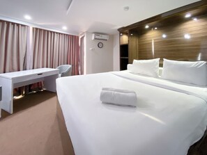 Ein Hotelzimmer mit einem Bett, einem Schreibtisch, einem Stuhl und einer Klimaanlage.