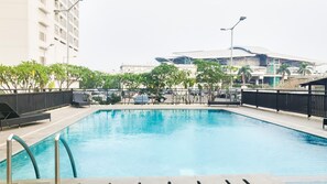 Una piscina con barandilla metálica, rodeada de una valla y árboles.