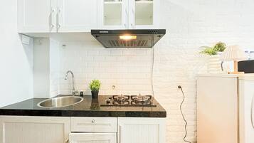 A kitchen with white cabinets, a stainless steel sink, a gas stove, and a white brick backsplash.