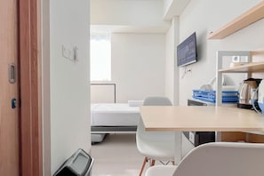Ein Hotelzimmer mit Bett, Schreibtisch, Stuhl, Fernseher und Mikrowelle.