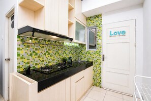 A kitchen with a black countertop, a stove, and a window with a 'Love' sign. - 1Br Apartment For 2 Pax At Teluk Intan (Jakarta)