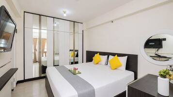 A hotel room with a bed, bedside table, TV, wardrobe, and a mirror.