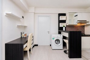 Eine kompakte Küche mit Waschmaschine, Essbereich mit Stuhl und kleinem Tisch.