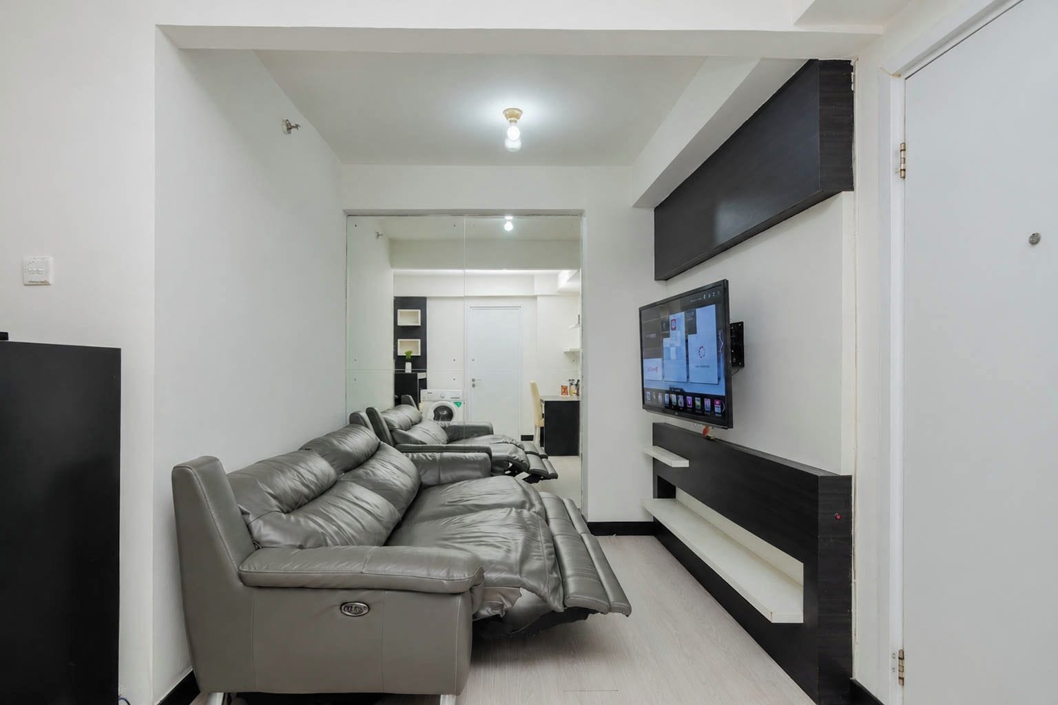 Un soggiorno moderno con un divano modulare grigio, una TV a schermo piatto montata a parete e un mobile TV a incasso.