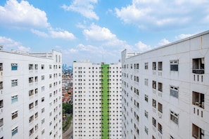 Un edificio de gran altura con varios pisos, destacando una franja verde central, y vistas despejadas del paisaje urbano circundante.